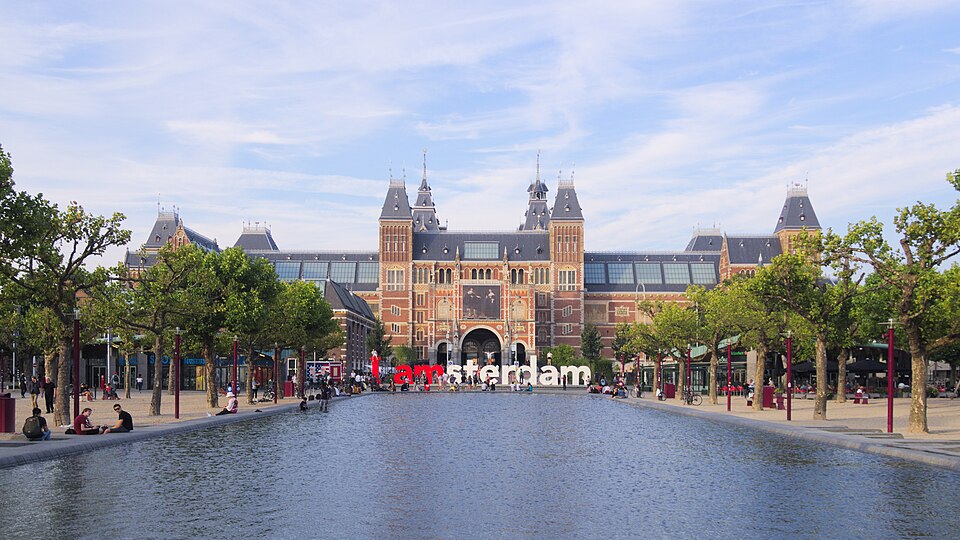 The Rijksmuseum across the pond on Museumplein, trees down both sides