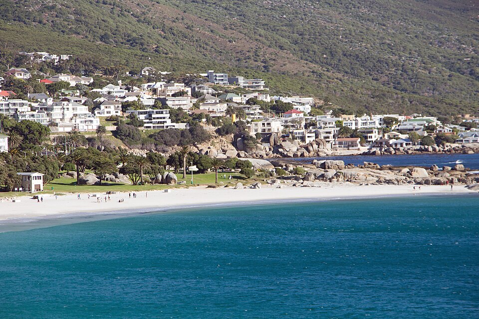 The white beach and turquoise water below villas on the mountain slope