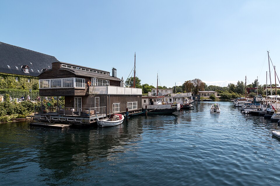 A timber house on the water and moored barges along the canal