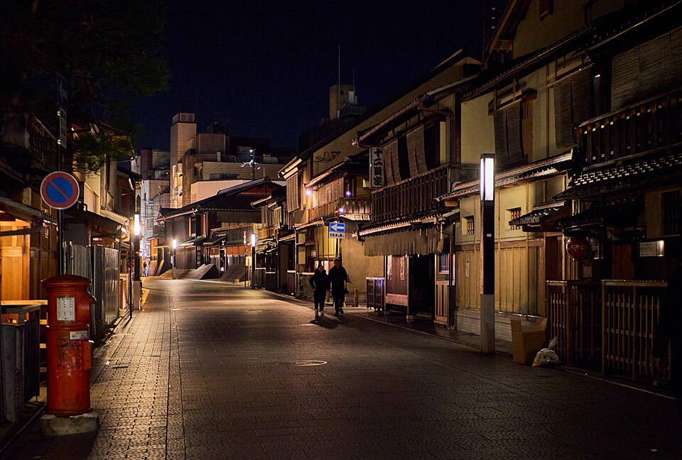 A Gion street at night, machiya frontages and lanterns along the cobbles