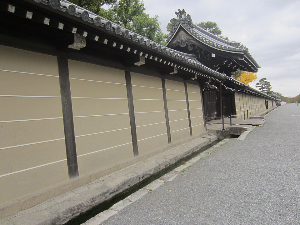 The long ochre wall of the imperial enclosure beside a gravel path