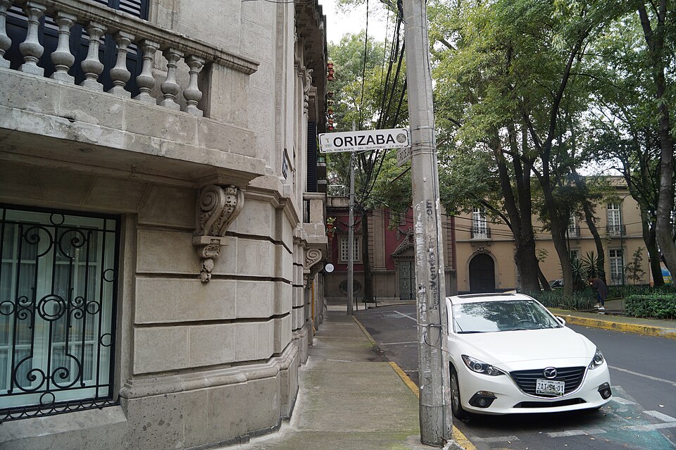 A stone corner building and the Orizaba street sign under trees