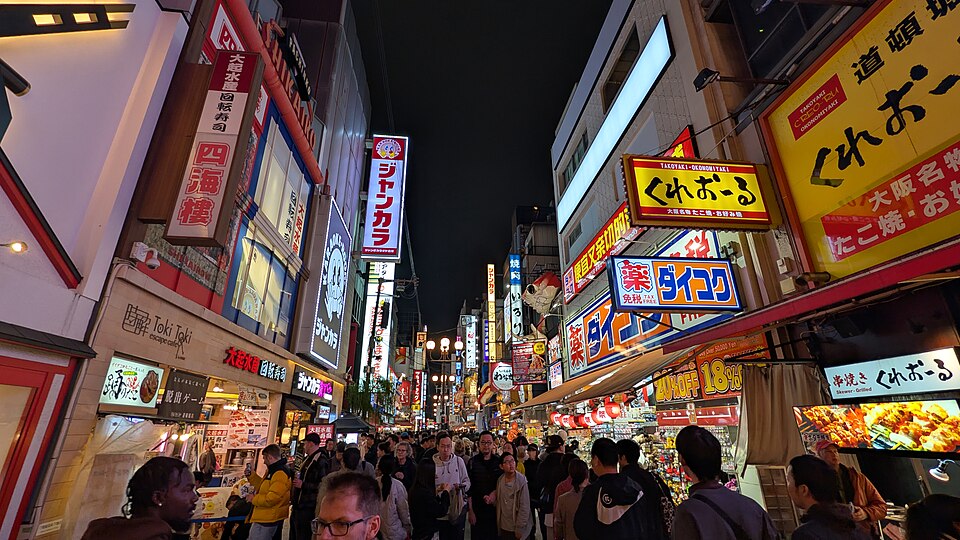 A Dōtonbori street at night packed with people under stacked neon signs