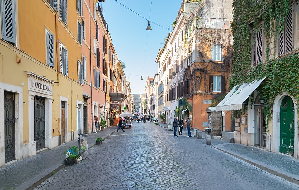 A cobbled street of shopfronts and awnings, the Vatican at the far end