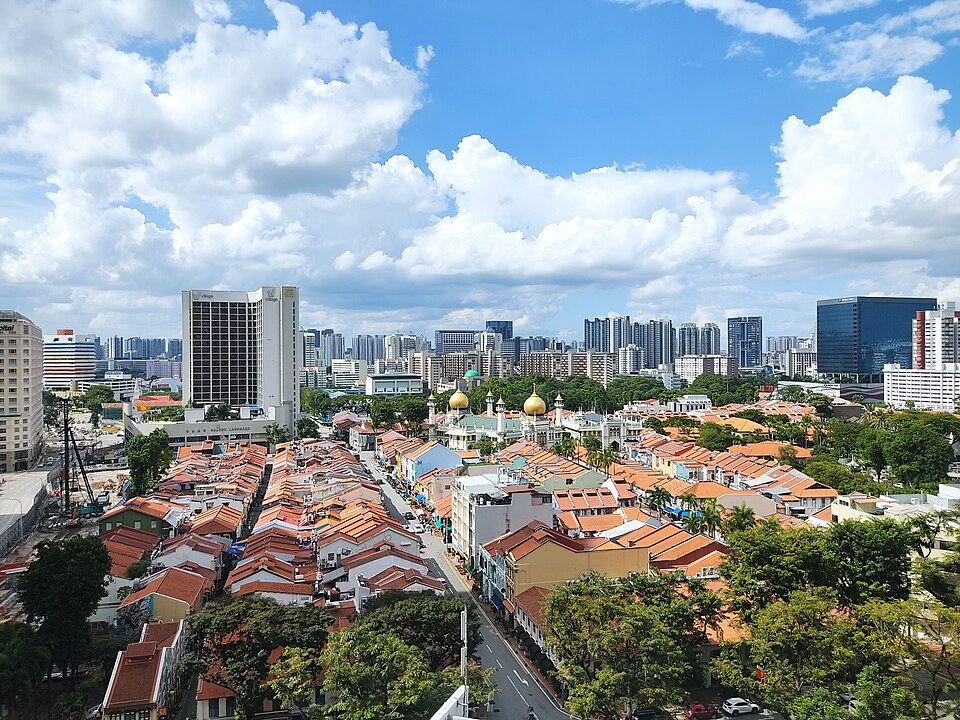 Orange-tiled shophouse roofs from above, a golden mosque dome among them