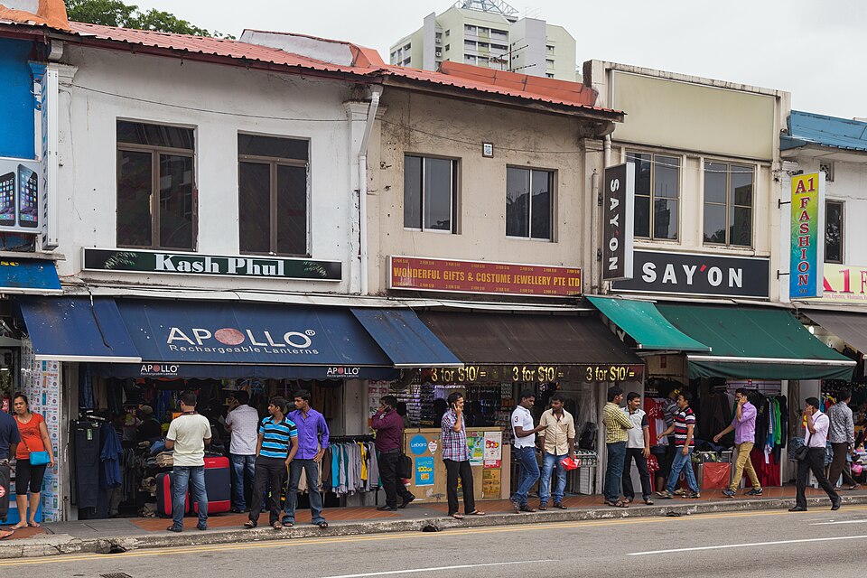 Shophouse frontages and awnings on Serangoon Road, shoppers on the pavement