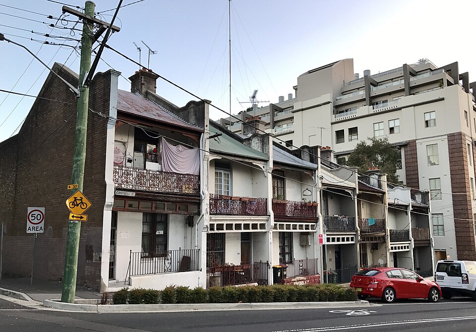 A row of Victorian terraces with iron lace balconies under power lines
