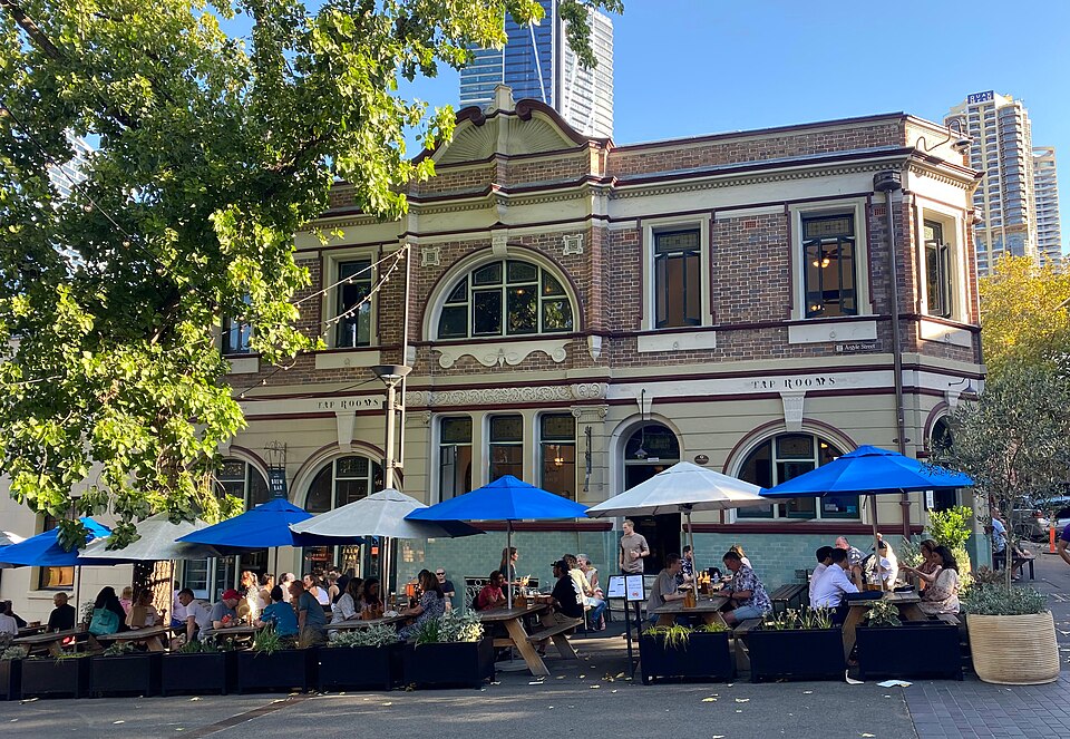 A Victorian pub on Argyle Street with tables under blue umbrellas, towers behind
