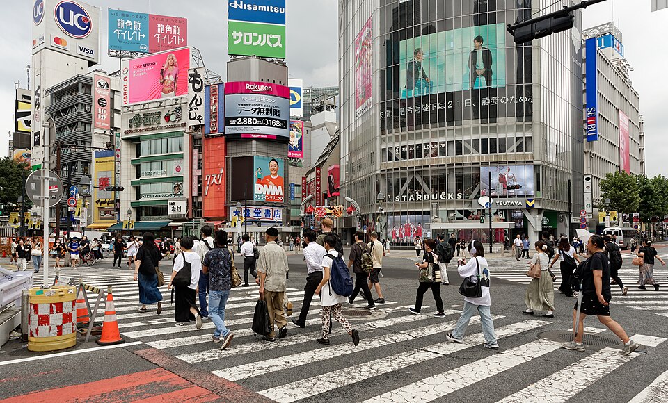 People crossing the Scramble in every direction, screens above